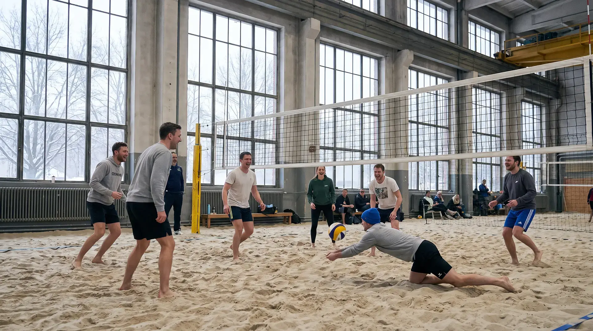 Grupp som spelar beachvolleyboll på sandplan i inomhushallen vintertid